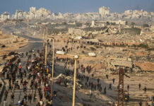 
			
				                                Israeli tanks are positioned on the coastal road leading to Gaza City as displaced Palestinians gather near Wadi Gaza in the central Gaza Strip on Thursday.
                                 AP Photo

			
		